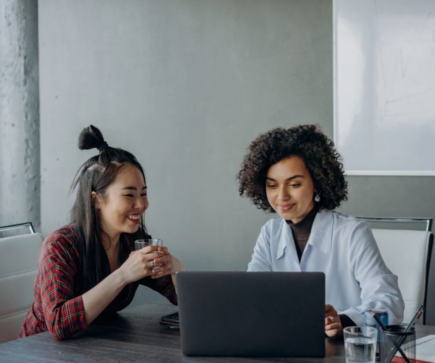 Women having a conversation while looking at the screen of a laptop